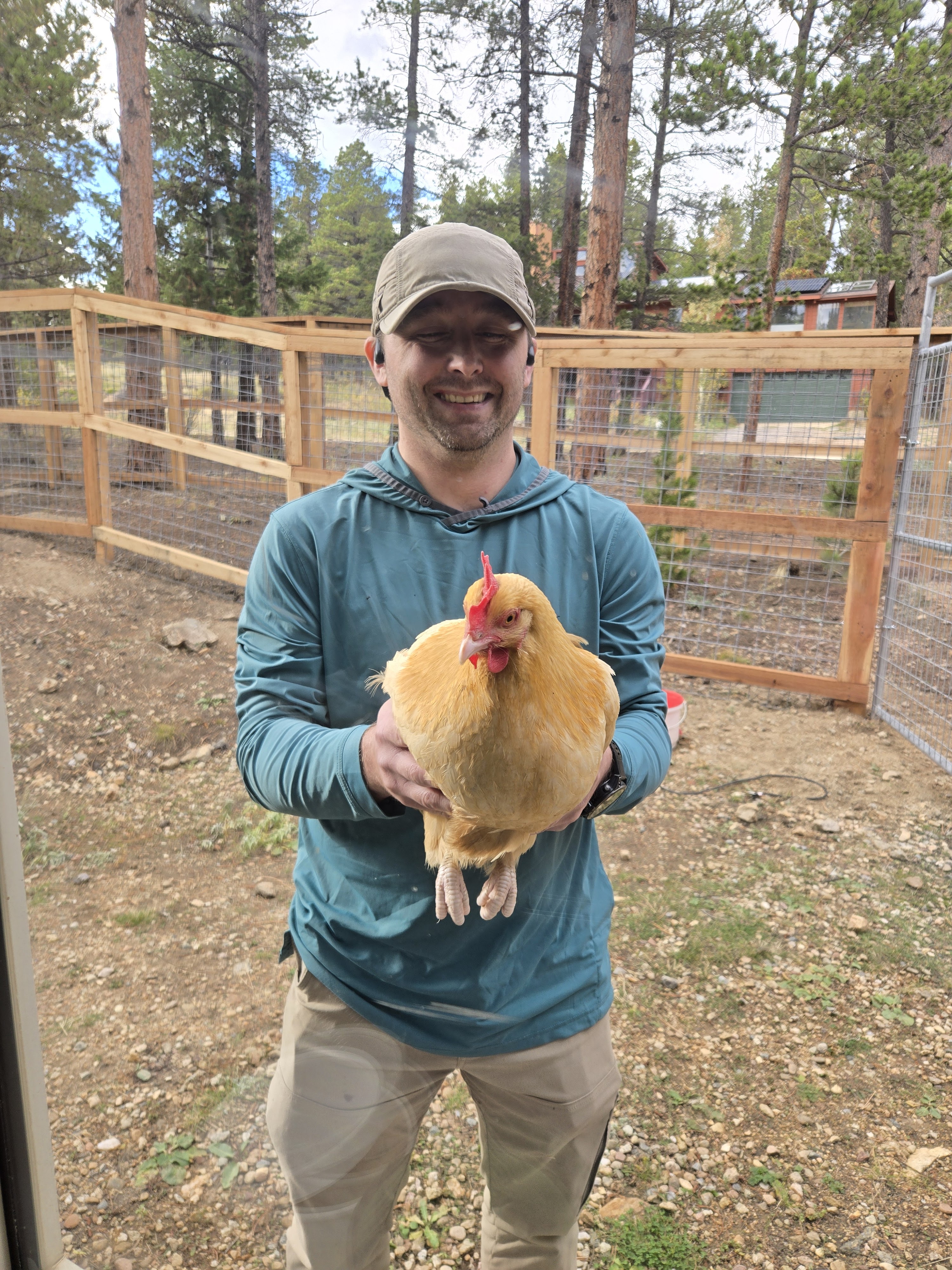 Man holding a chicken out in front of himself, smiling